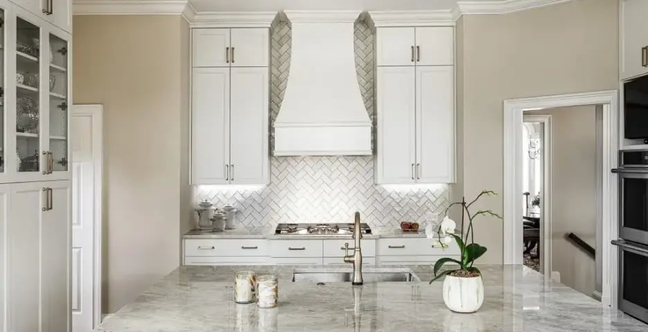 Sophisticated kitchen with marble countertops and herringbone backsplash.