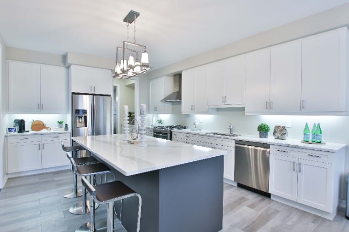  Spacious kitchen with white cabinetry, quartz countertops, and a chic hanging chandelier