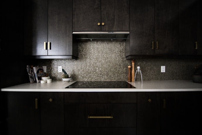 Modern kitchen with dark cabinetry, herringbone backsplash, and brass hardware accents