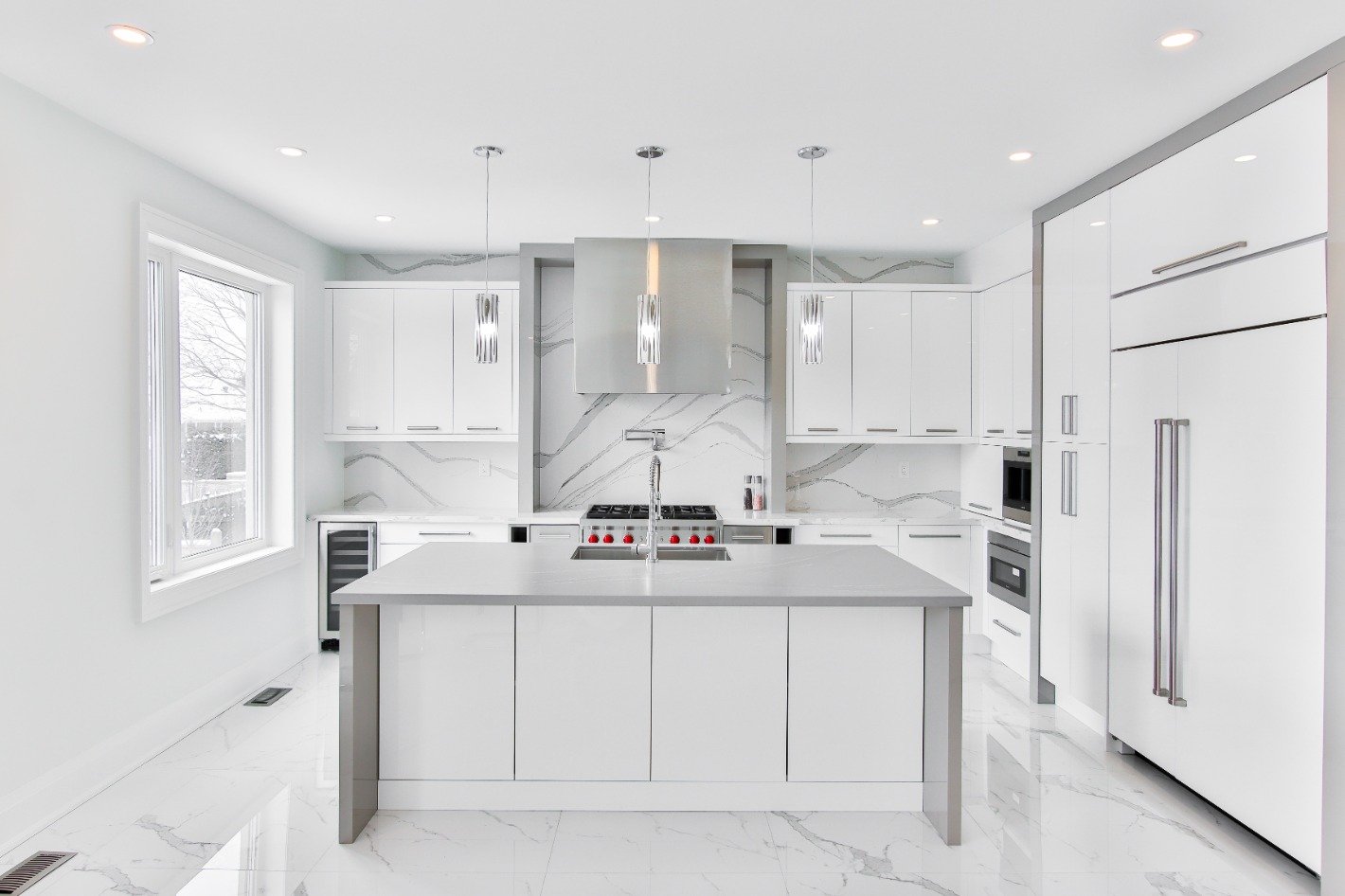 Bright white modern kitchen with marble floors, sleek cabinetry, and stylish pendant lights
