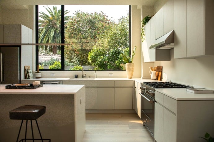  Warmly lit modern kitchen with a large window view, neutral tones, and a minimalist design