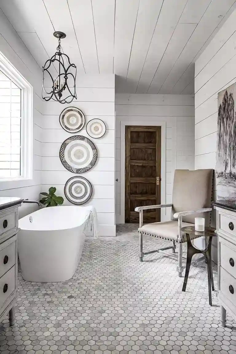 Elegant white bathroom featuring freestanding tub, decorative wall plates, and hexagon tile flooring
