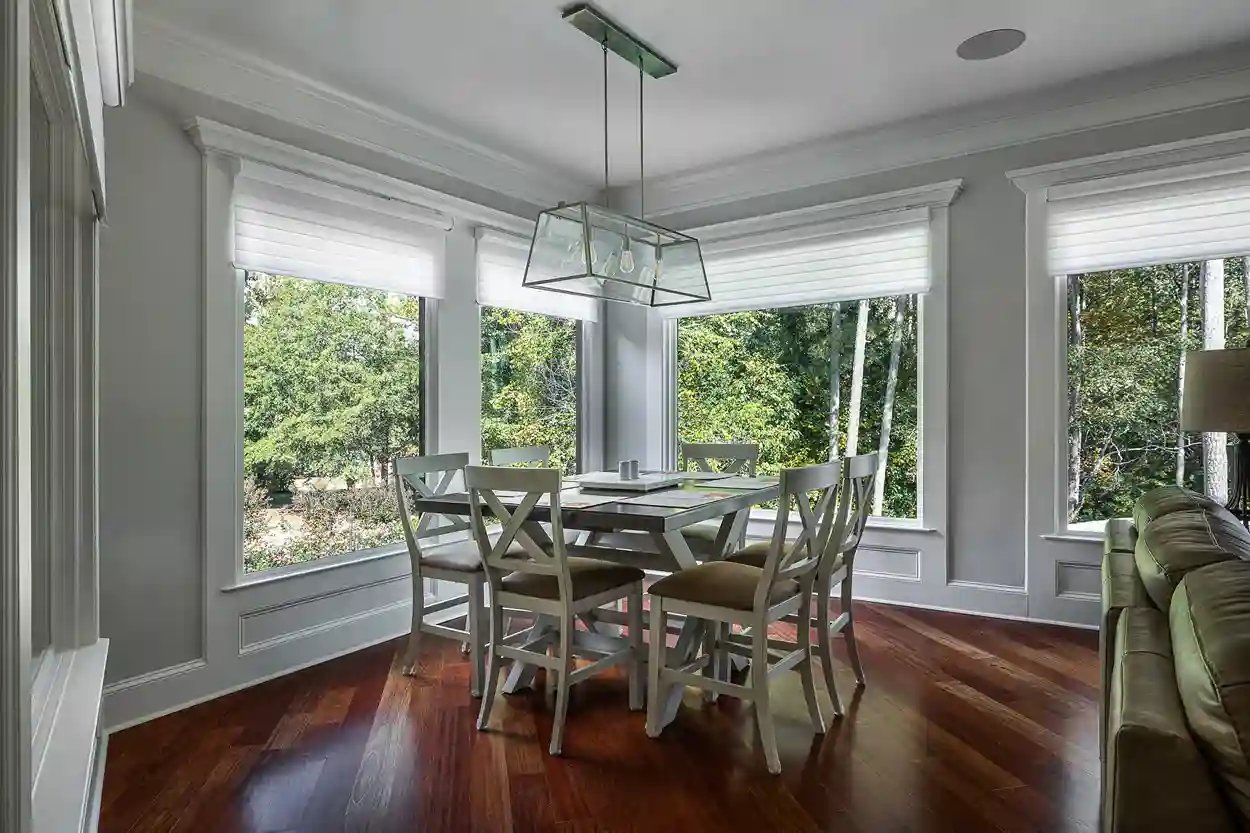 Bright dining area with large windows, a modern light fixture, and a view of greenery outside.
