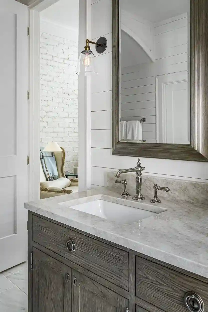 Elegant bathroom with distressed wood vanity, marble countertop, and classic sconce light over mirror