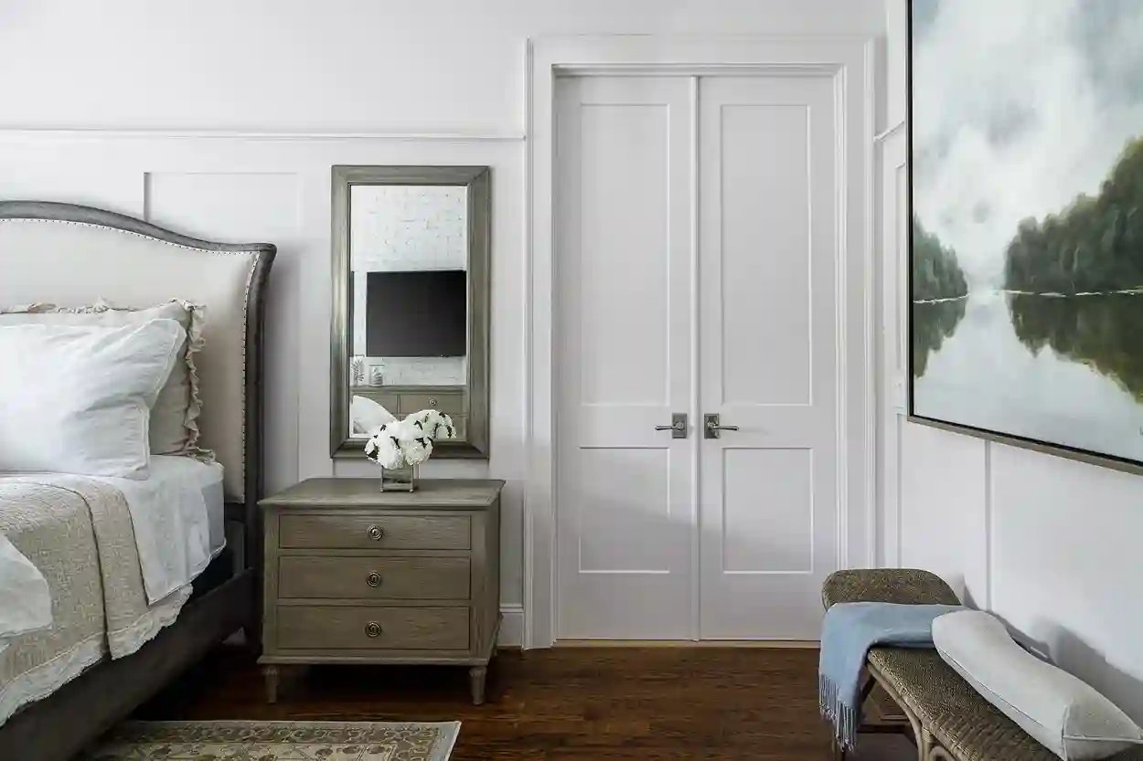Elegant bedroom with upholstered headboard, mirrored nightstand, and large landscape painting