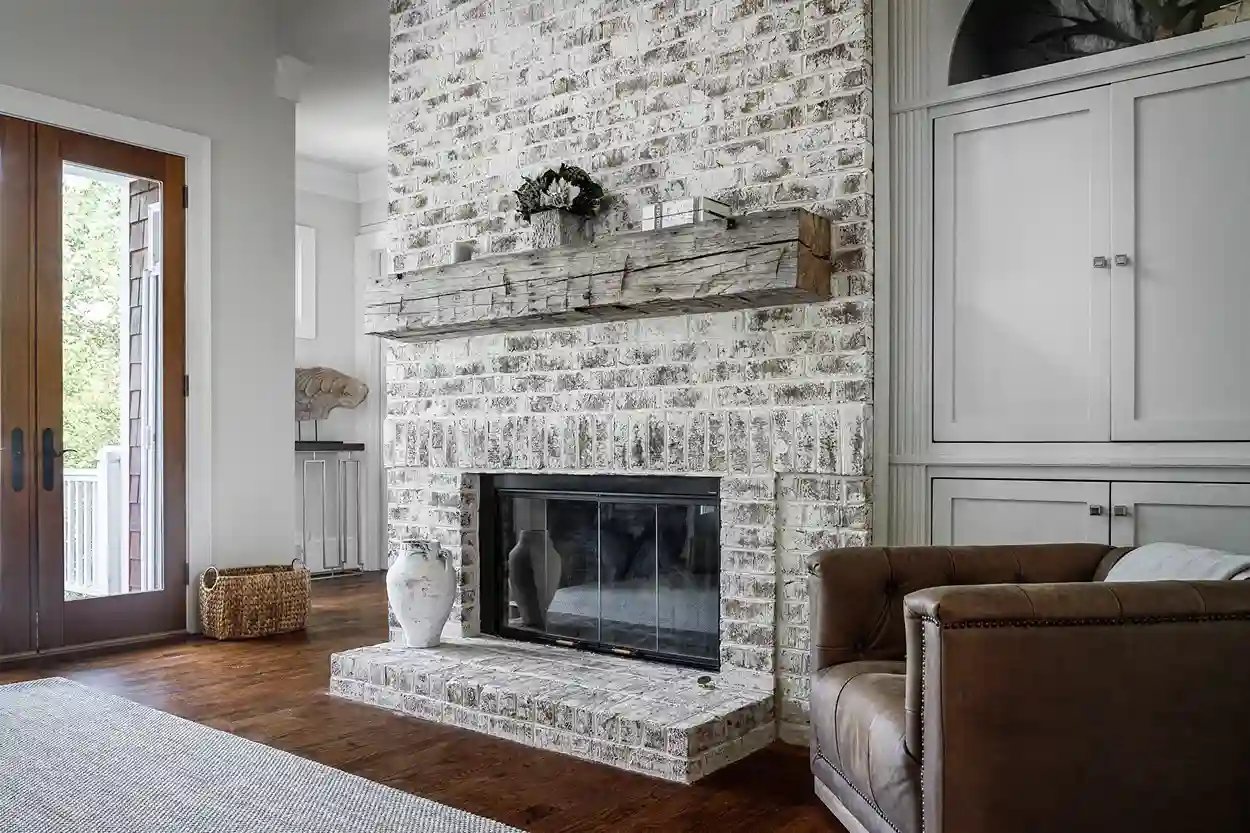Living room featuring a white brick fireplace, rustic mantel, and leather sofa