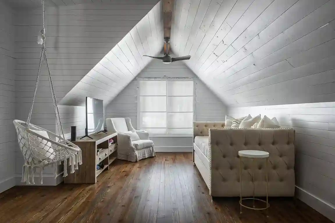 Attic lounge area with hanging chair, plush sofa, and wooden floors