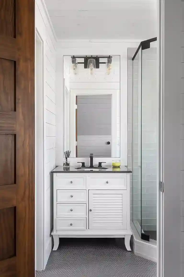  Chic bathroom vanity with black fixtures, subway tile shower, and industrial-style lights.