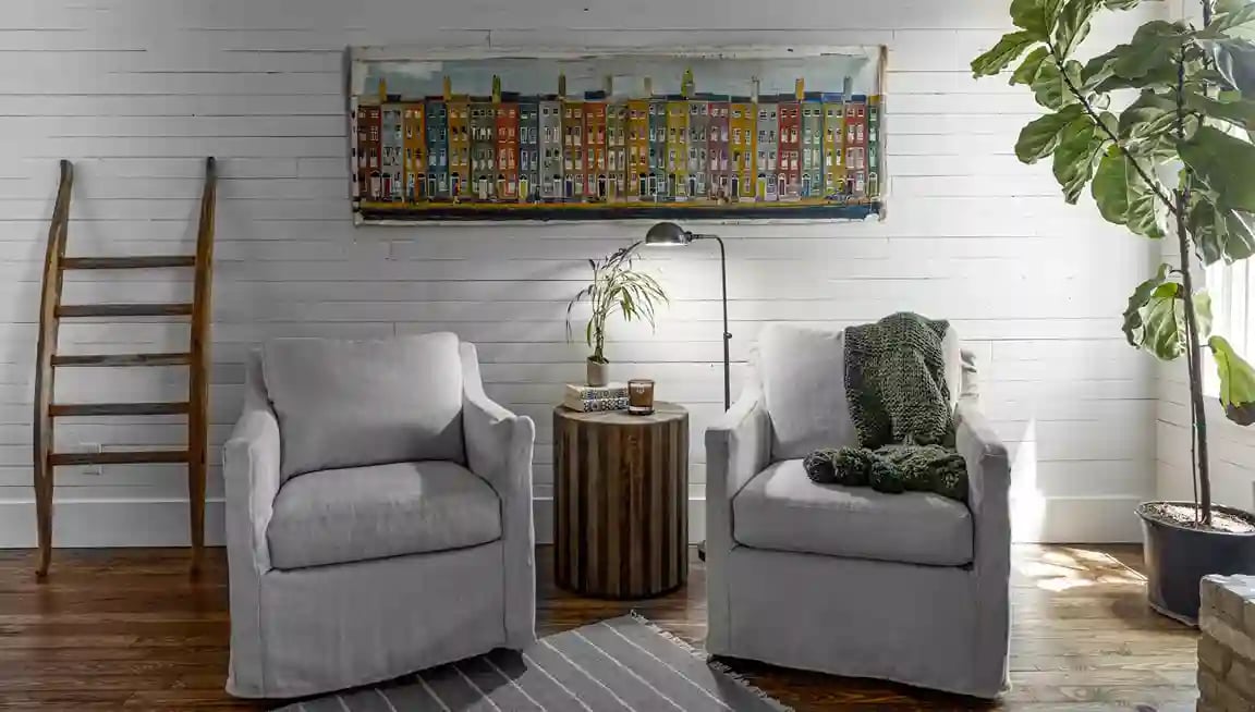  Cozy reading nook with twin armchairs, shiplap walls, and vibrant street scene artwork.