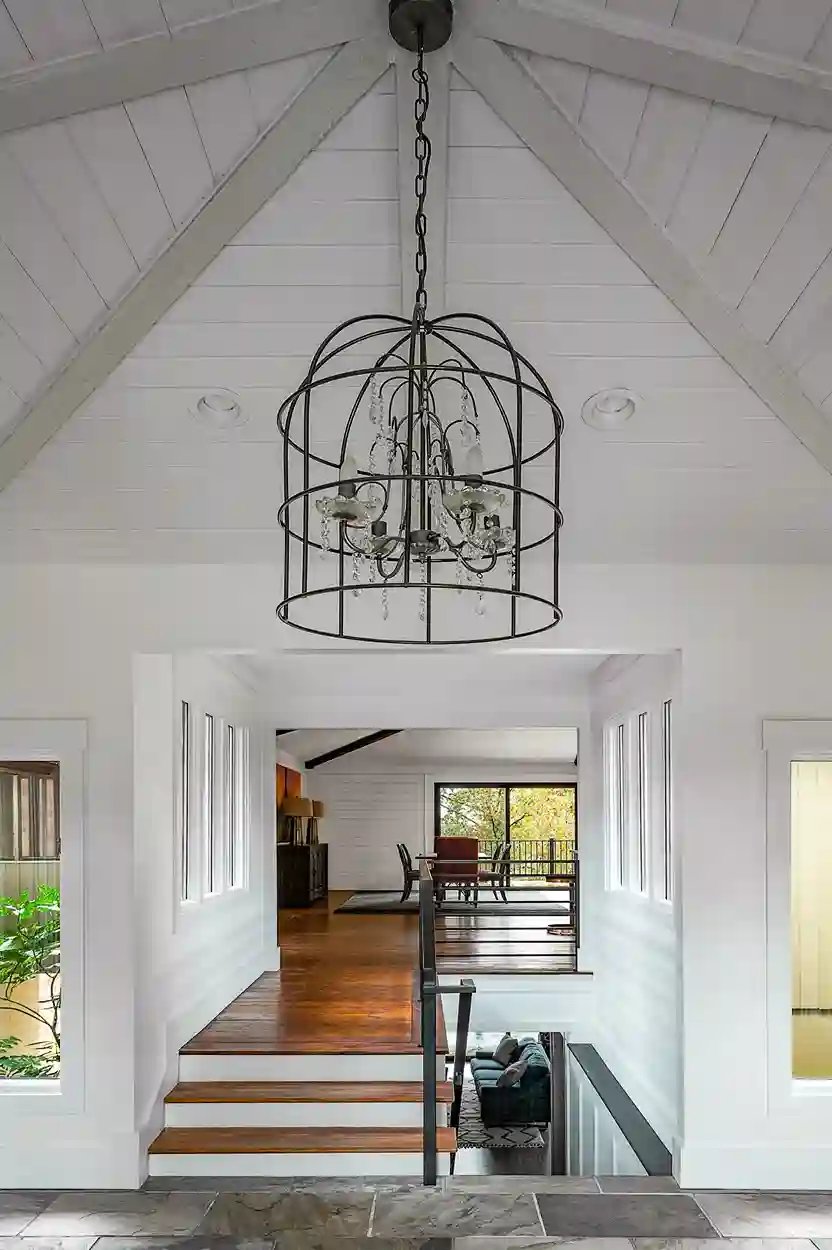 Vaulted ceiling entryway with a cage-style chandelier and view into living space.