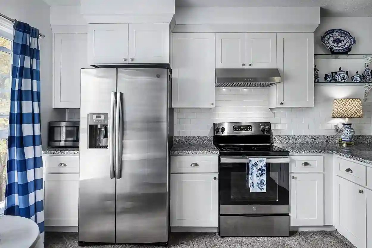 Compact kitchen with white cabinets, granite countertops, and stainless steel appliances.