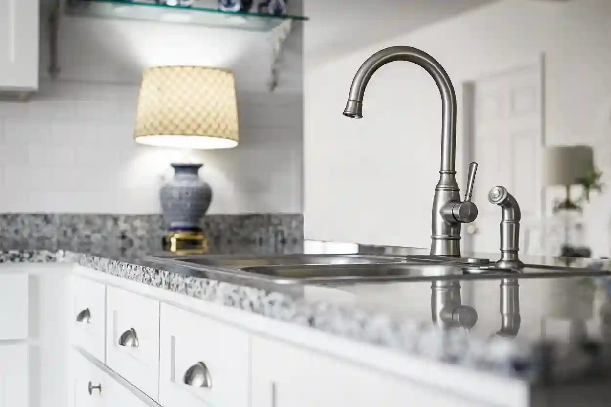 Elegant kitchen countertop with textured backsplash, gooseneck faucet, and decorative lamp.