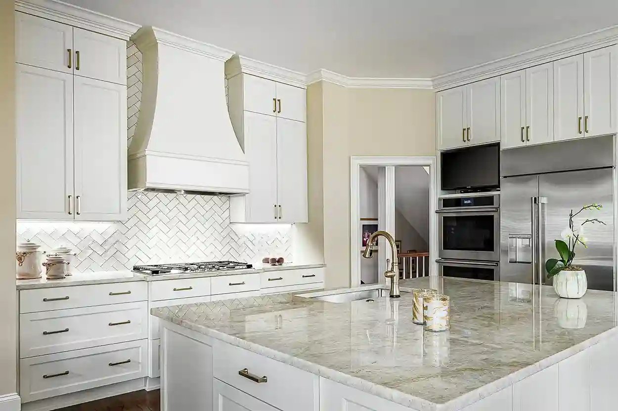 Bright kitchen with white cabinetry, herringbone backsplash, and granite countertops.