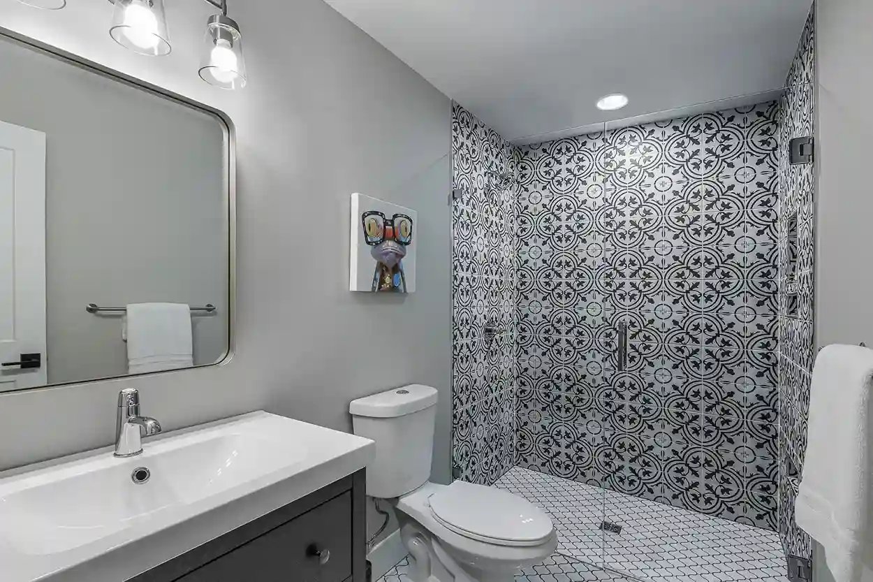 Modern bathroom with patterned tiles, sleek vanity, and framed mirror.