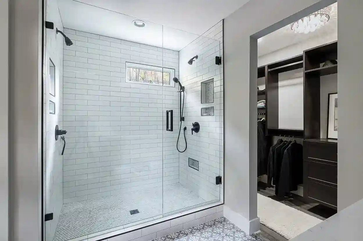  Spacious bathroom with subway-tiled walk-in shower, black hardware, and adjacent walk-in closet.