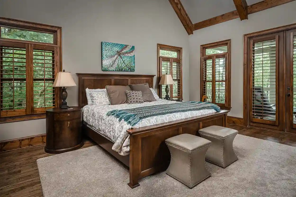 Cozy bedroom with exposed wooden beams, large windows, and dragonfly artwork