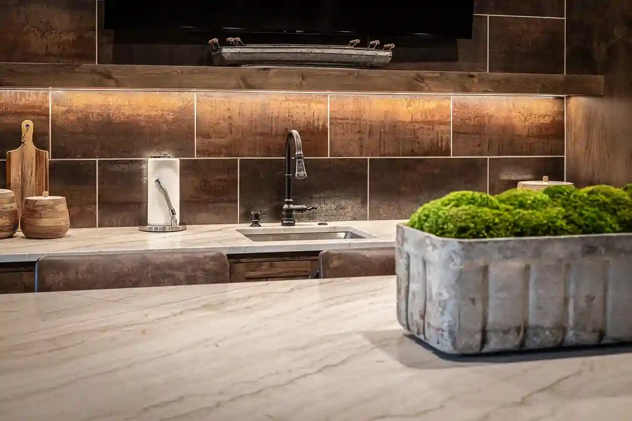 Rustic kitchen counter with textured backsplash, marble top, and a unique moss planter as decor.