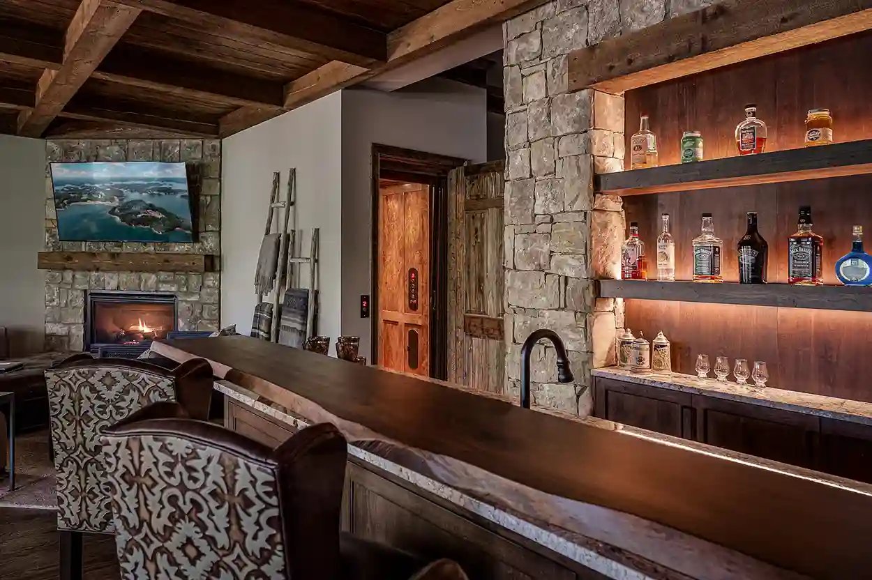 Home bar with stone accent wall, fireplace, and wooden details in a living room