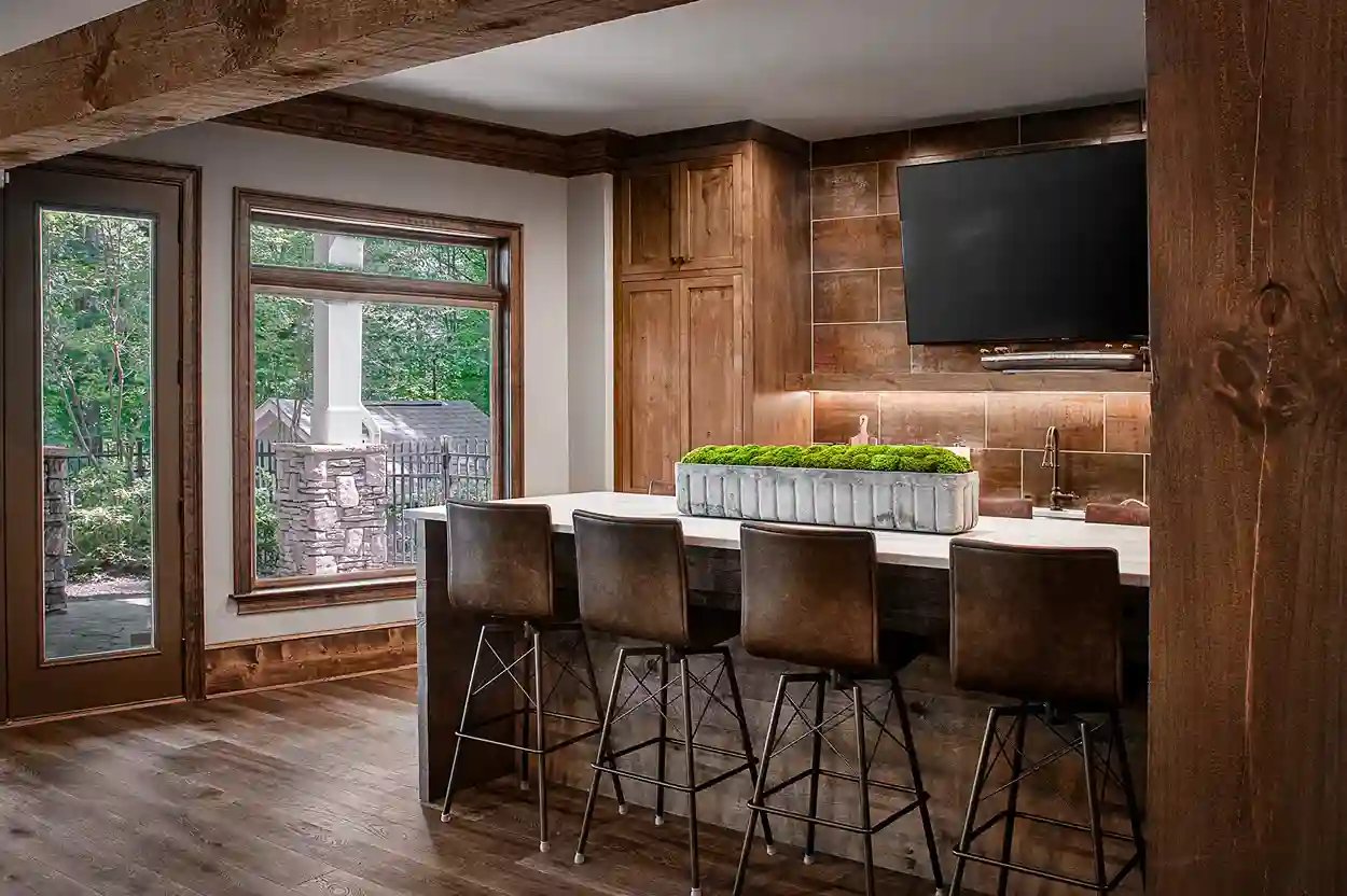 Custom indoor bar with wooden cabinets and leather stools in a modern home by Michael James Remodeling.