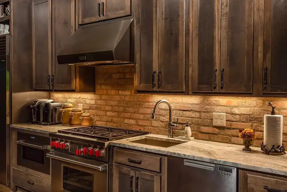 Chic kitchen with dark wood cabinets, stainless steel appliances, and exposed brick backsplash