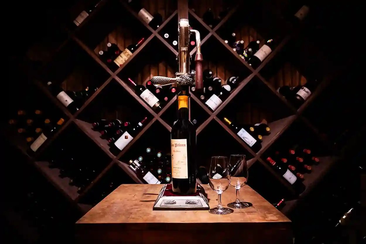 Private wine cellar with a bottle of red wine and glasses on a wooden table.