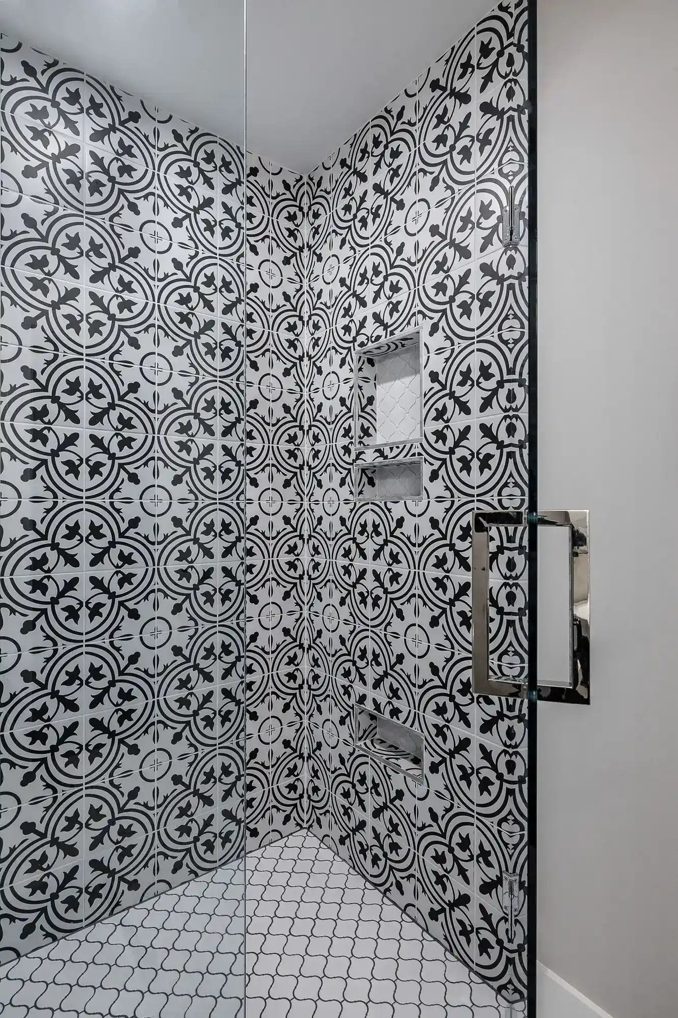 Monochromatic bathroom shower with bold patterned tiles and a modern glass door