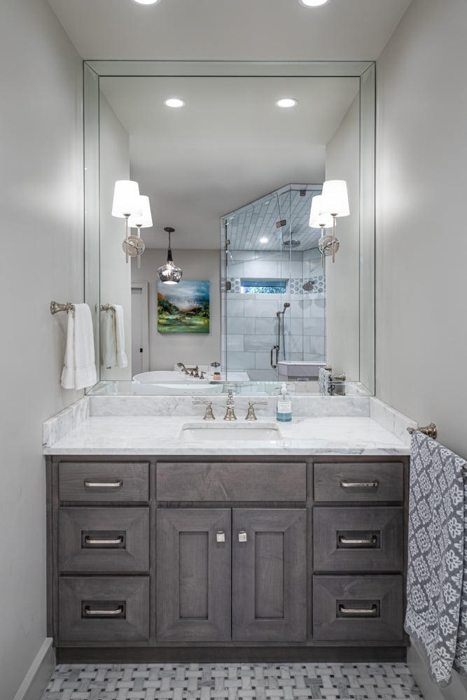 Modern bathroom vanity with marble countertop, large mirror, and stylish pendant lights.