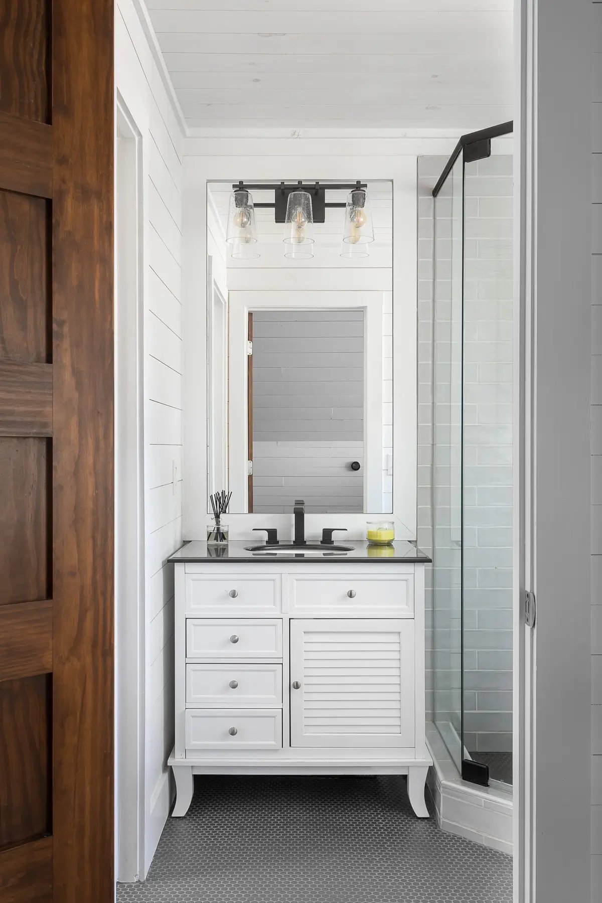 Chic bathroom vanity with black fixtures, subway tile shower, and industrial-style lights.