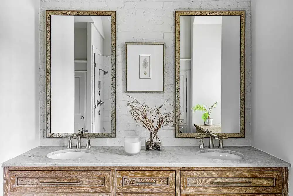Contemporary bathroom with double vanity, antique mirrors, and white marble countertop.