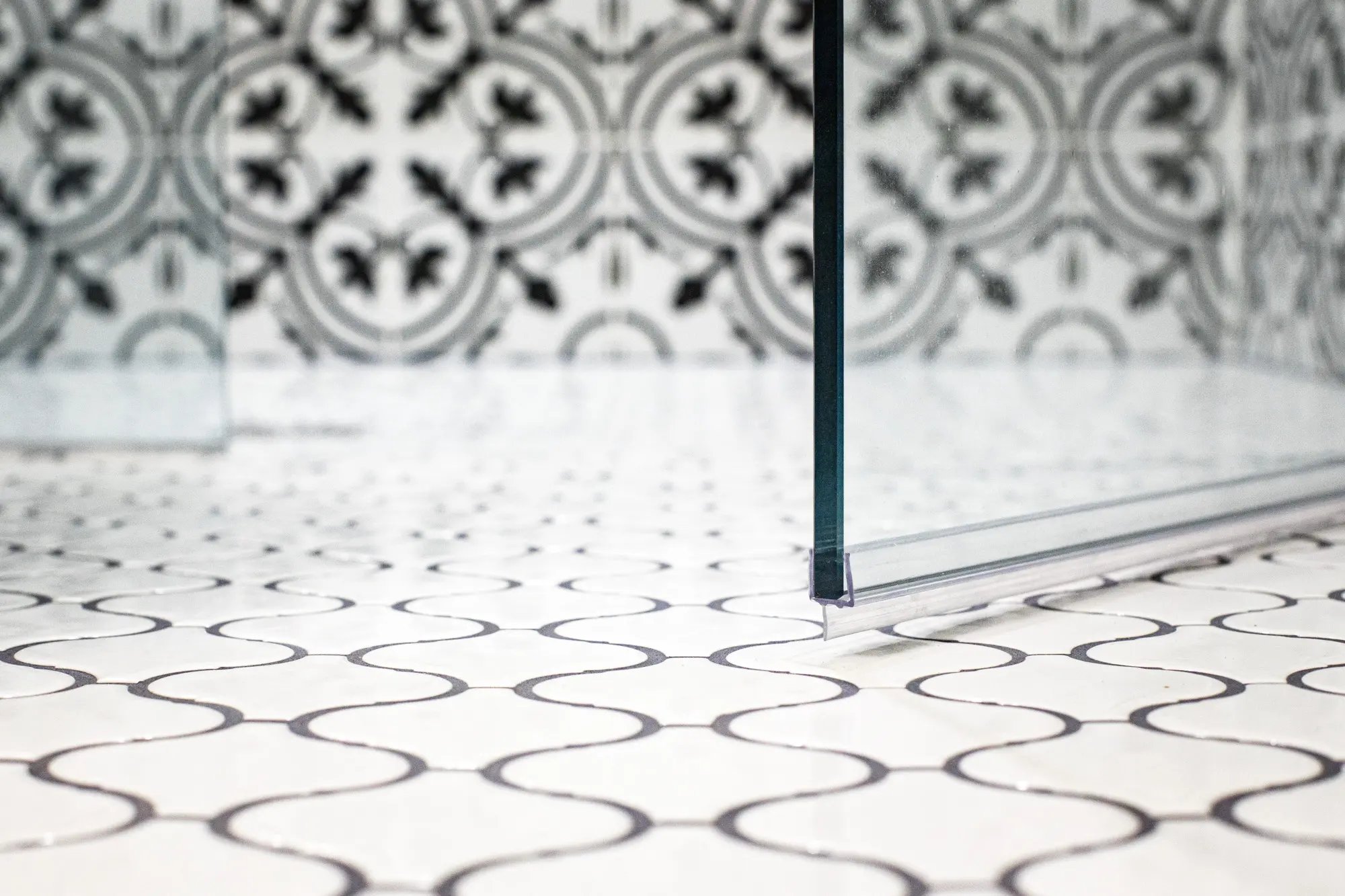 Detailed shot of patterned bathroom floor tiles with a clear glass shower partition