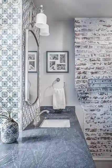 Bathroom corner with patterned tiles, granite countertop, and exposed distressed brick wall