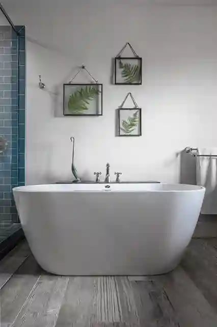Freestanding white bathtub with wall-mounted art in a serene bathroom.