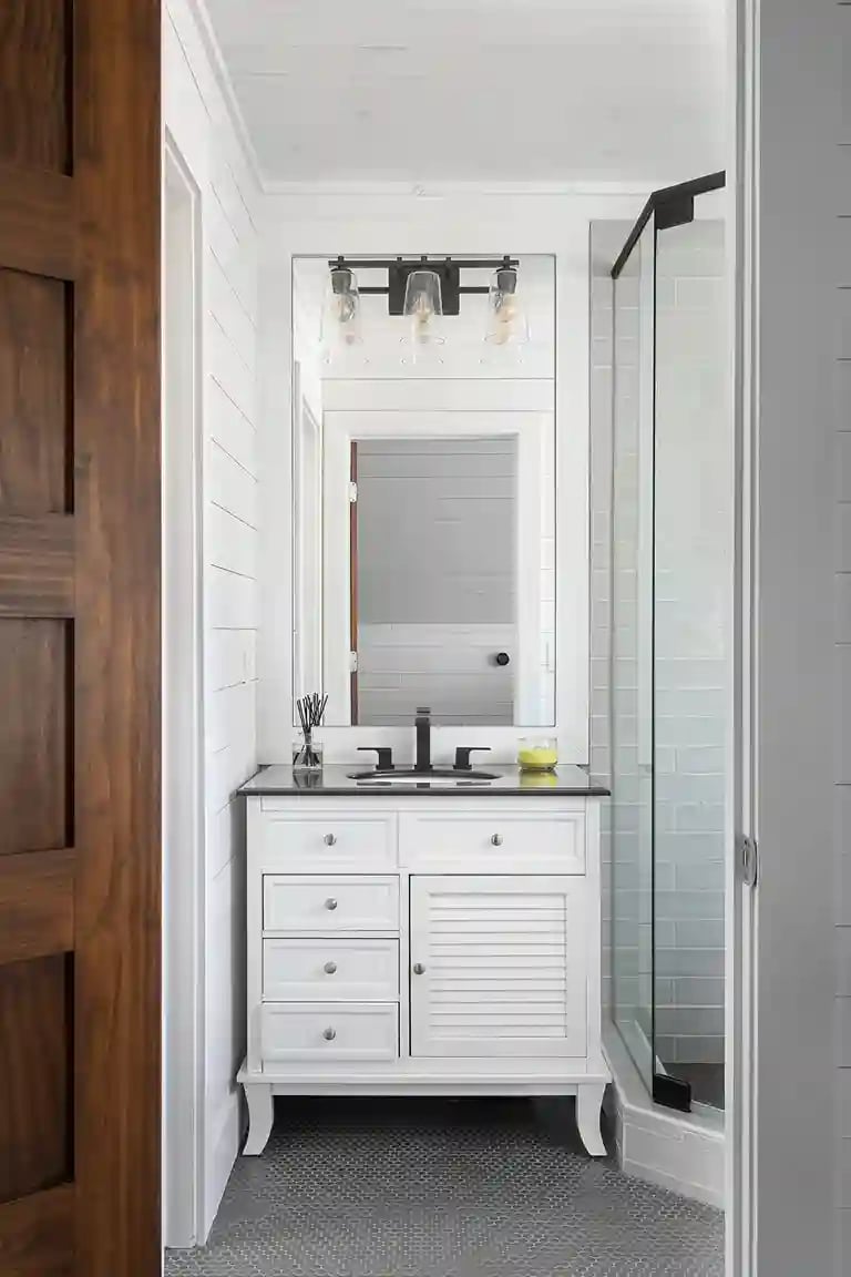 Chic bathroom vanity with black fixtures, subway tile shower, and industrial-style lights