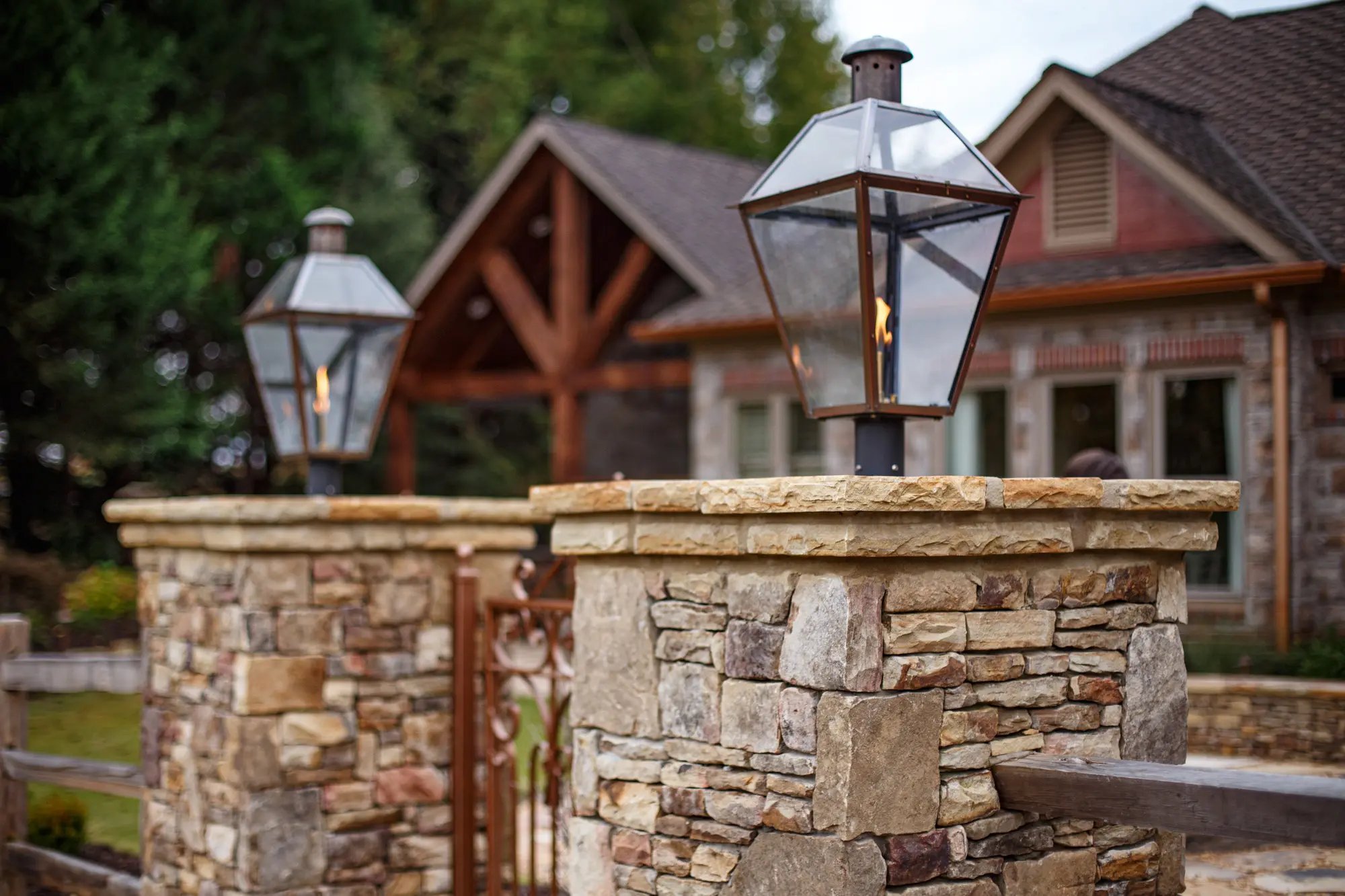 Traditional stone pillar with elegant gas lanterns in front of a luxury home