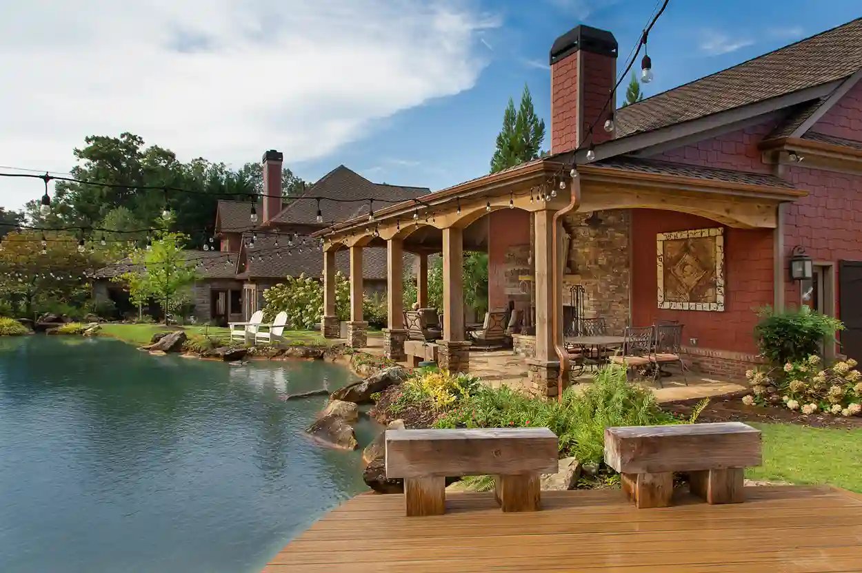 Luxurious lakeside outdoor living area with seating, string lights, and waterfront view.