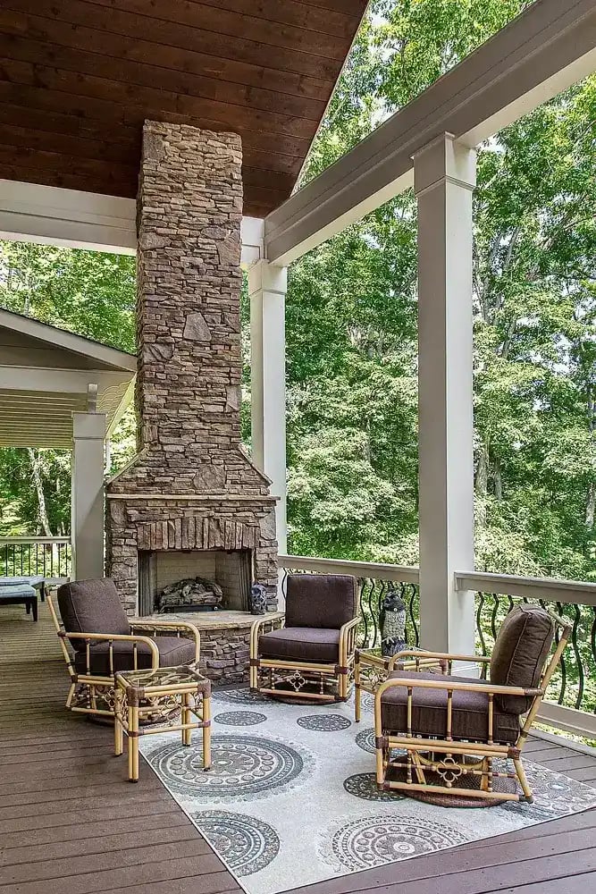 Covered outdoor patio with stone fireplace and comfortable seating by Michael James Remodeling.