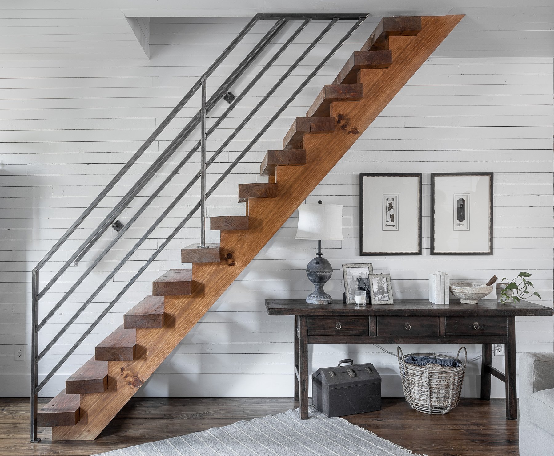 Modern minimalist home interior with floating wooden staircase, shiplap walls, and a chic console table.