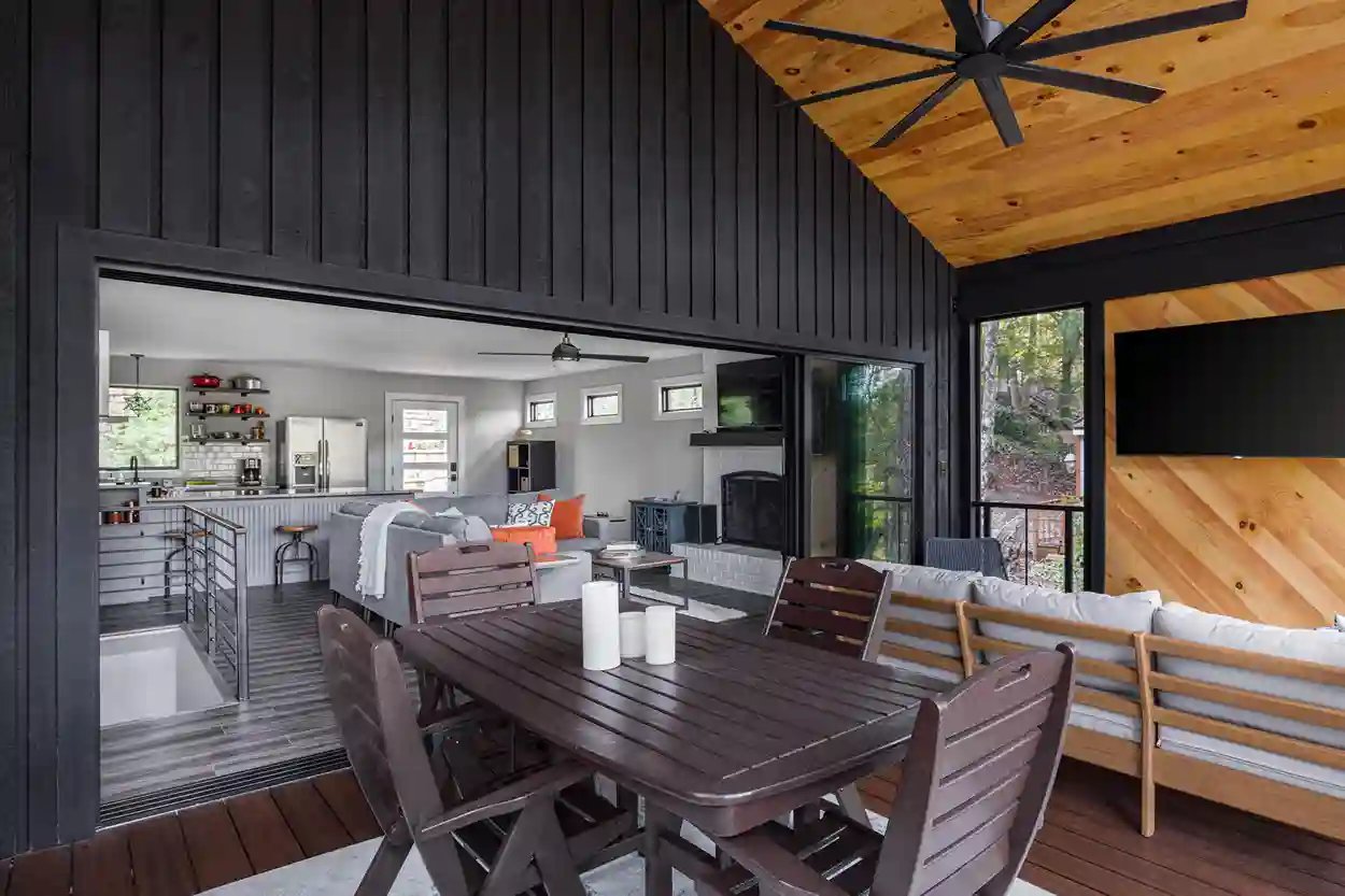 Inviting screened porch with dining area and comfortable lounge space, connected to a modern kitchen.