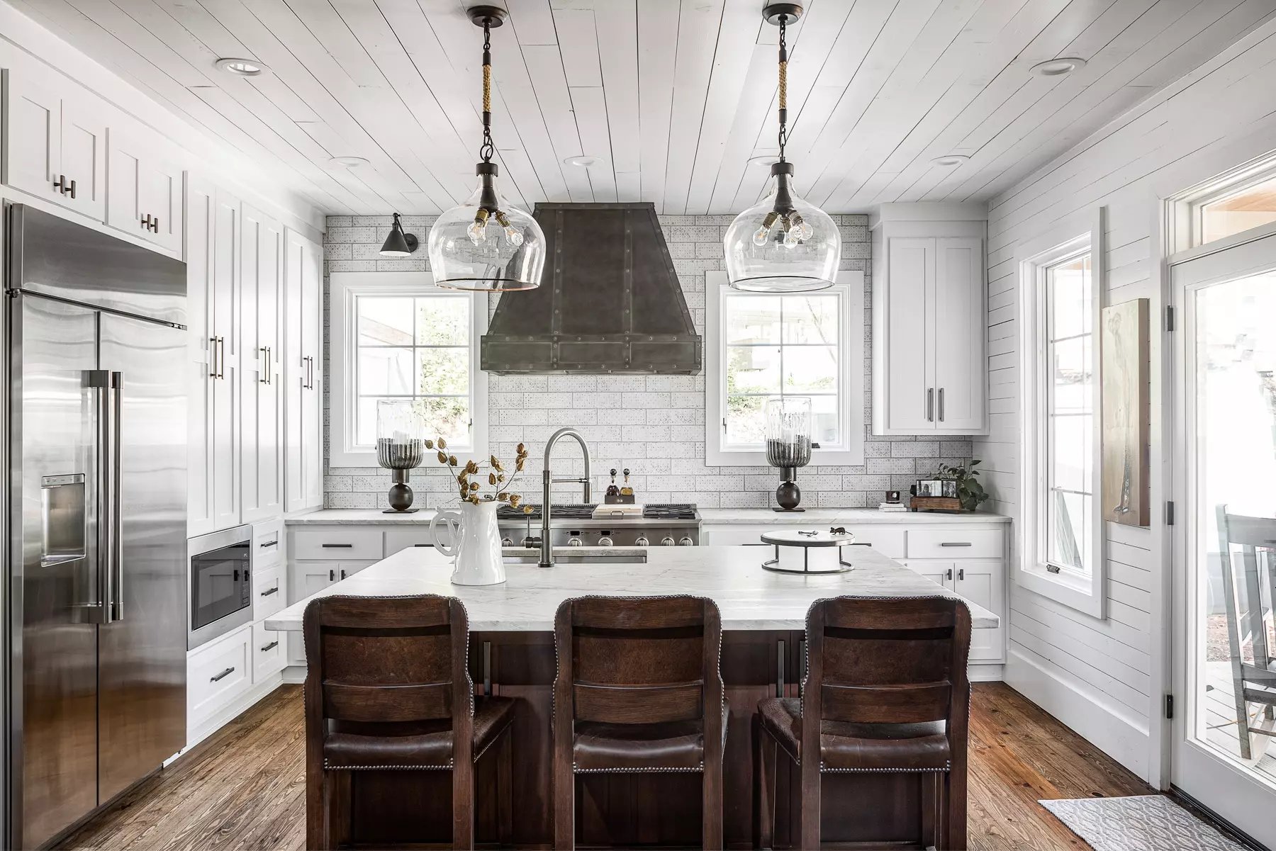 Bright farmhouse kitchen with shiplap walls, subway tiles, and statement lighting over the island.