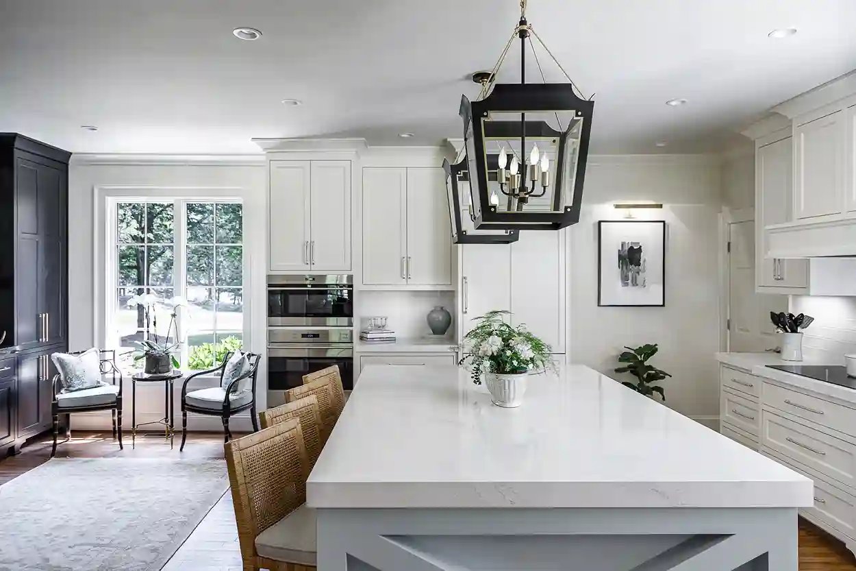 Elegant white kitchen with marble countertops, a central island, and a classic pendant light, creating a luxurious and inviting space.