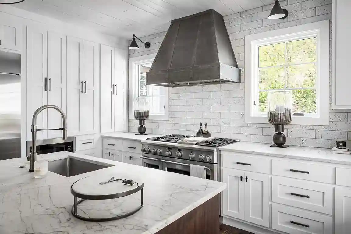 Elegant white kitchen with subway tiles, stainless steel appliances, and marble countertops