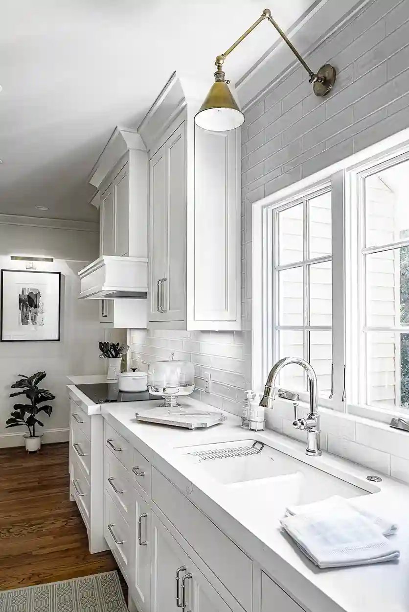 Bright white kitchen featuring a deep farmhouse sink, subway tile backsplash, and vintage brass light fixture.