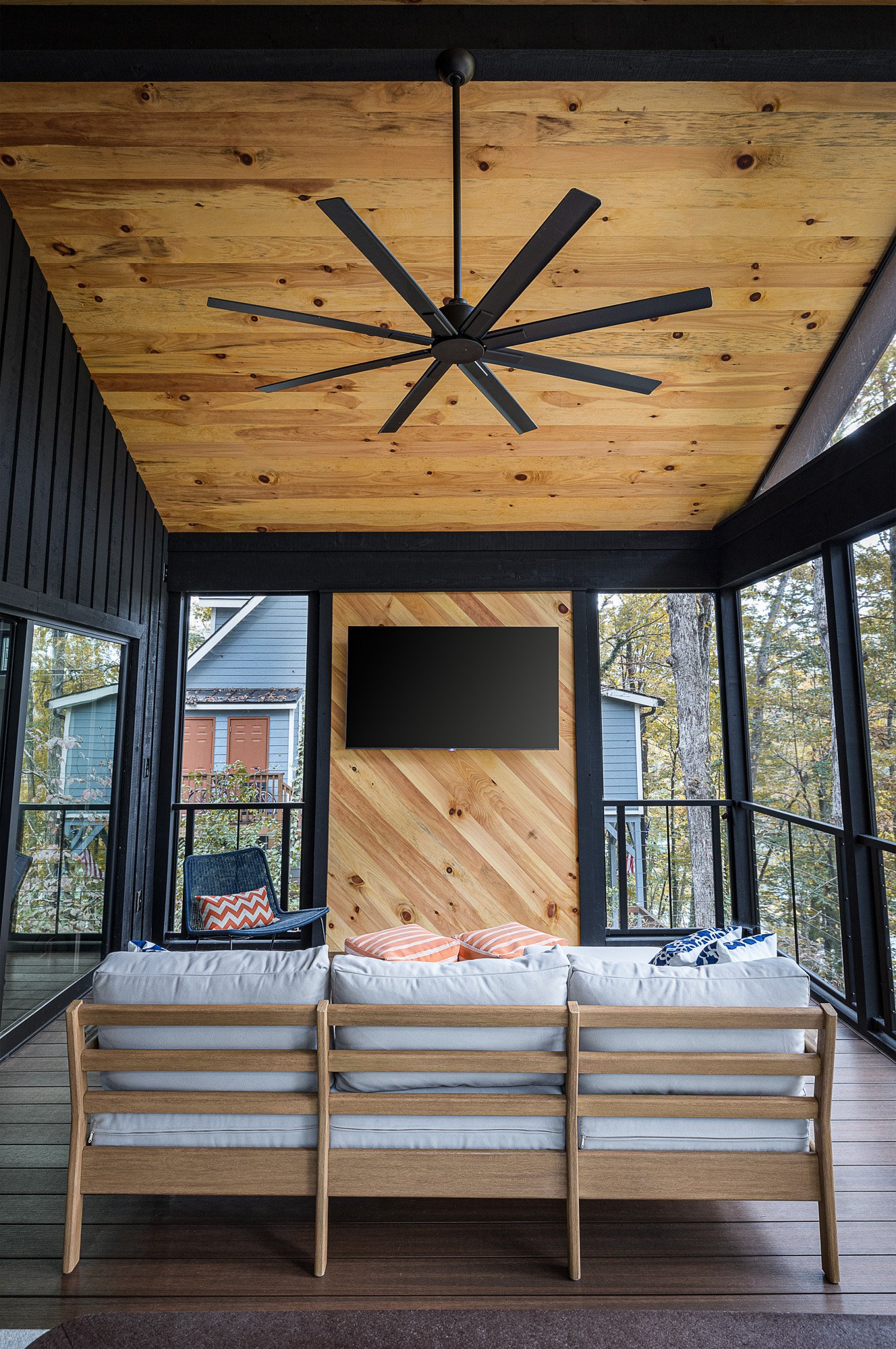 Chic porch with vaulted pine ceiling, large ceiling fan, and stylish outdoor seating area.