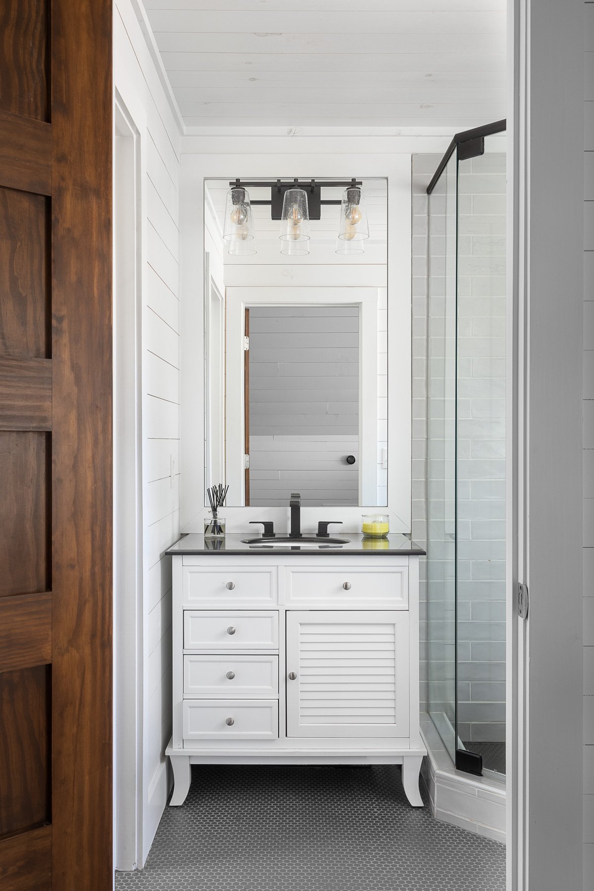Modern bathroom with white vanity, subway tiles, and industrial-style lighting.