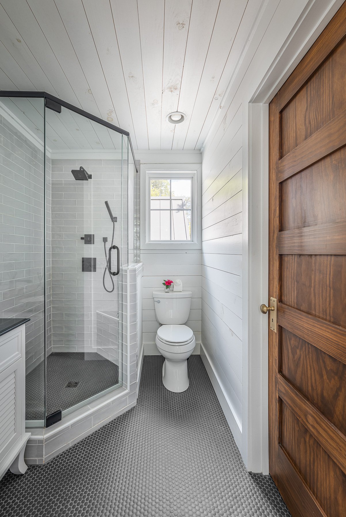 Contemporary bathroom with glass shower, white shiplap walls, and hexagon tile floor.