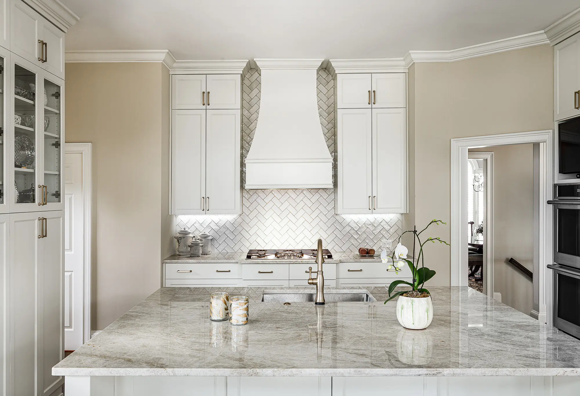 Bright kitchen with white cabinetry, herringbone backsplash, and granite countertops.