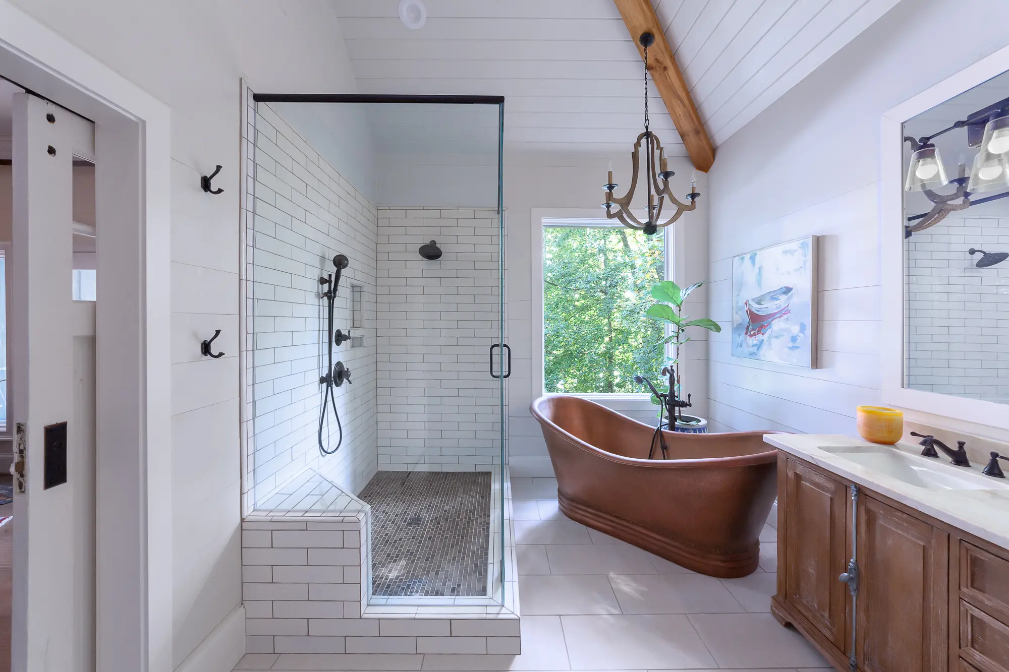 Farmhouse-style primary bathroom with copper tub and picture window by Michael James Remodeling